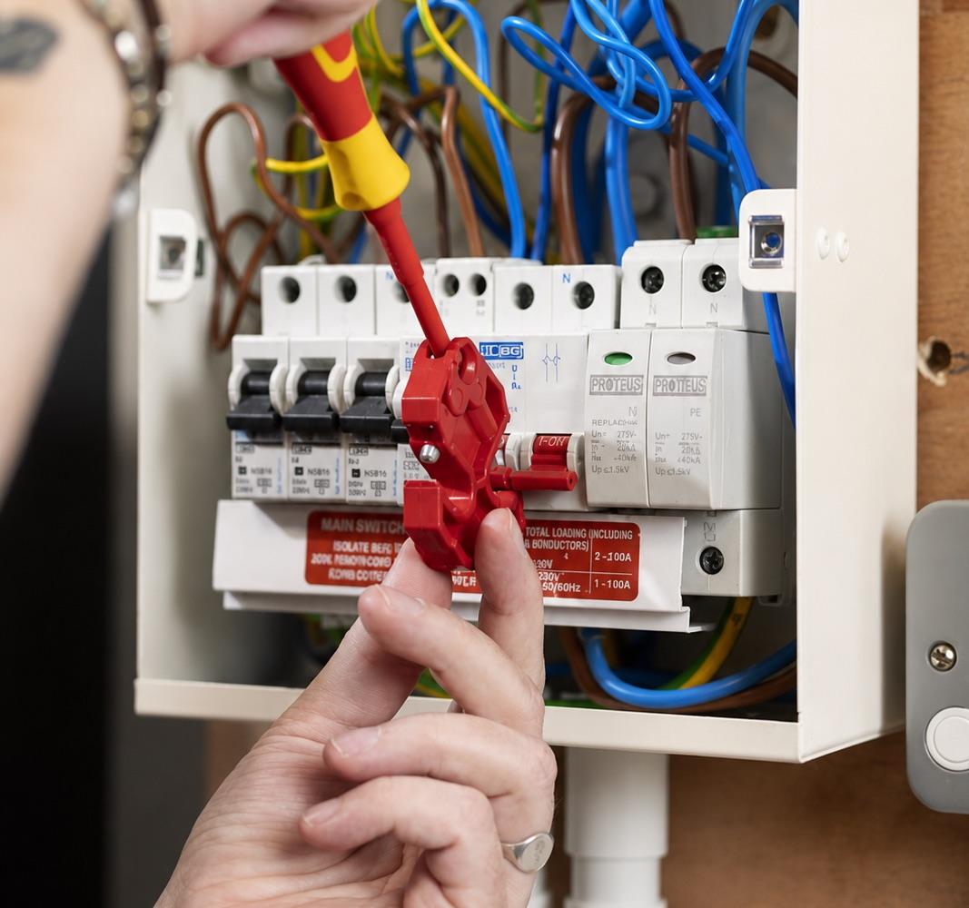 An electrician isolating a consumer unit with a safety lockout before working on it